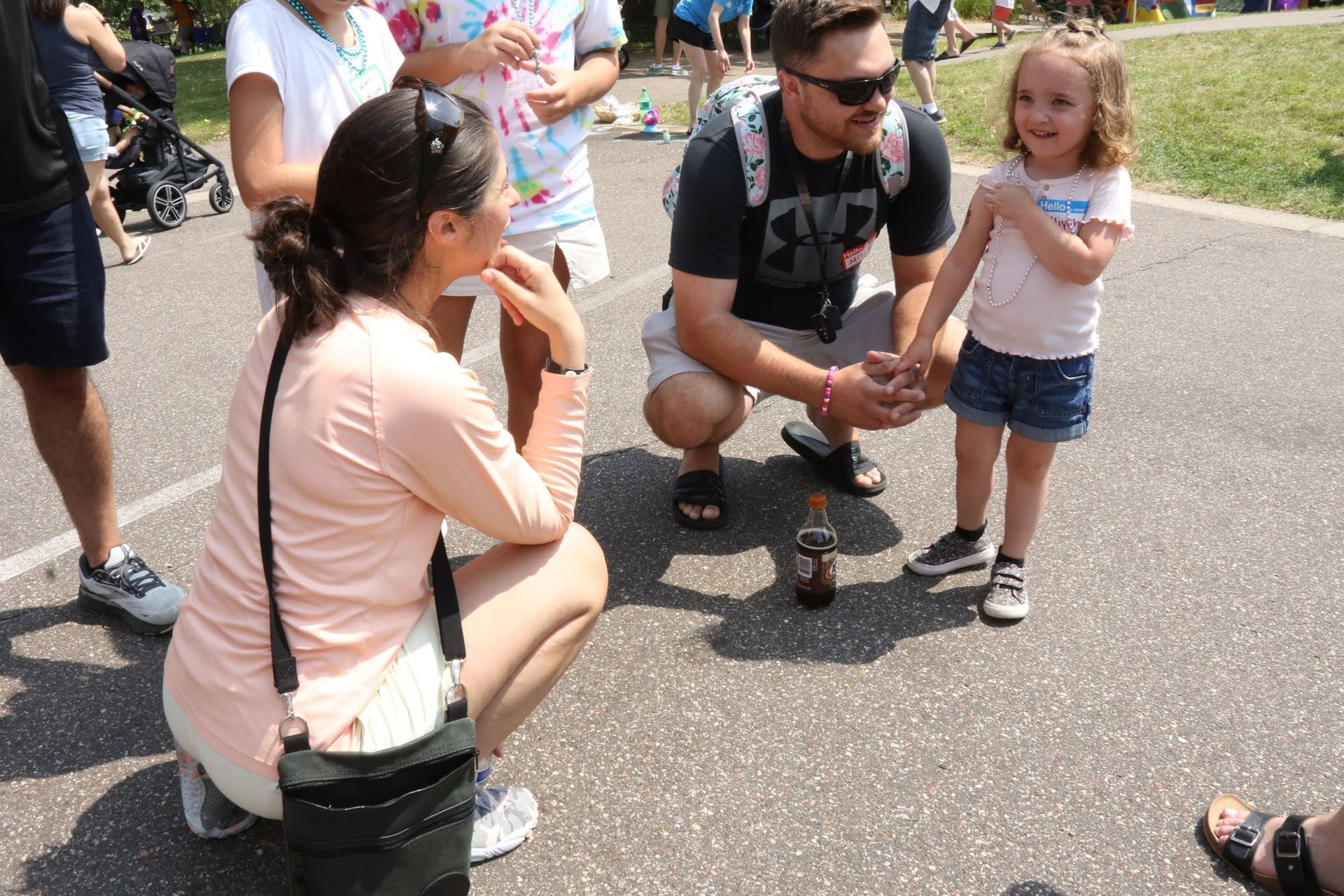 Two adults and a child on pavement. Man and woman squatting; the child smiles.