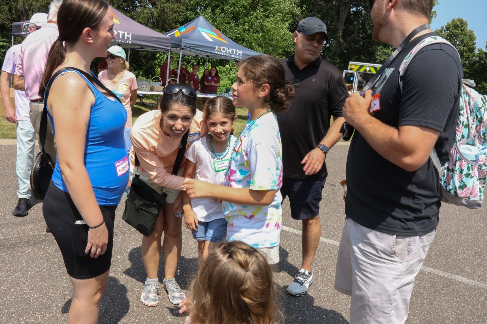 People at an outdoor event. Two women, two girls, and two men are gathered, possibly interacting.
