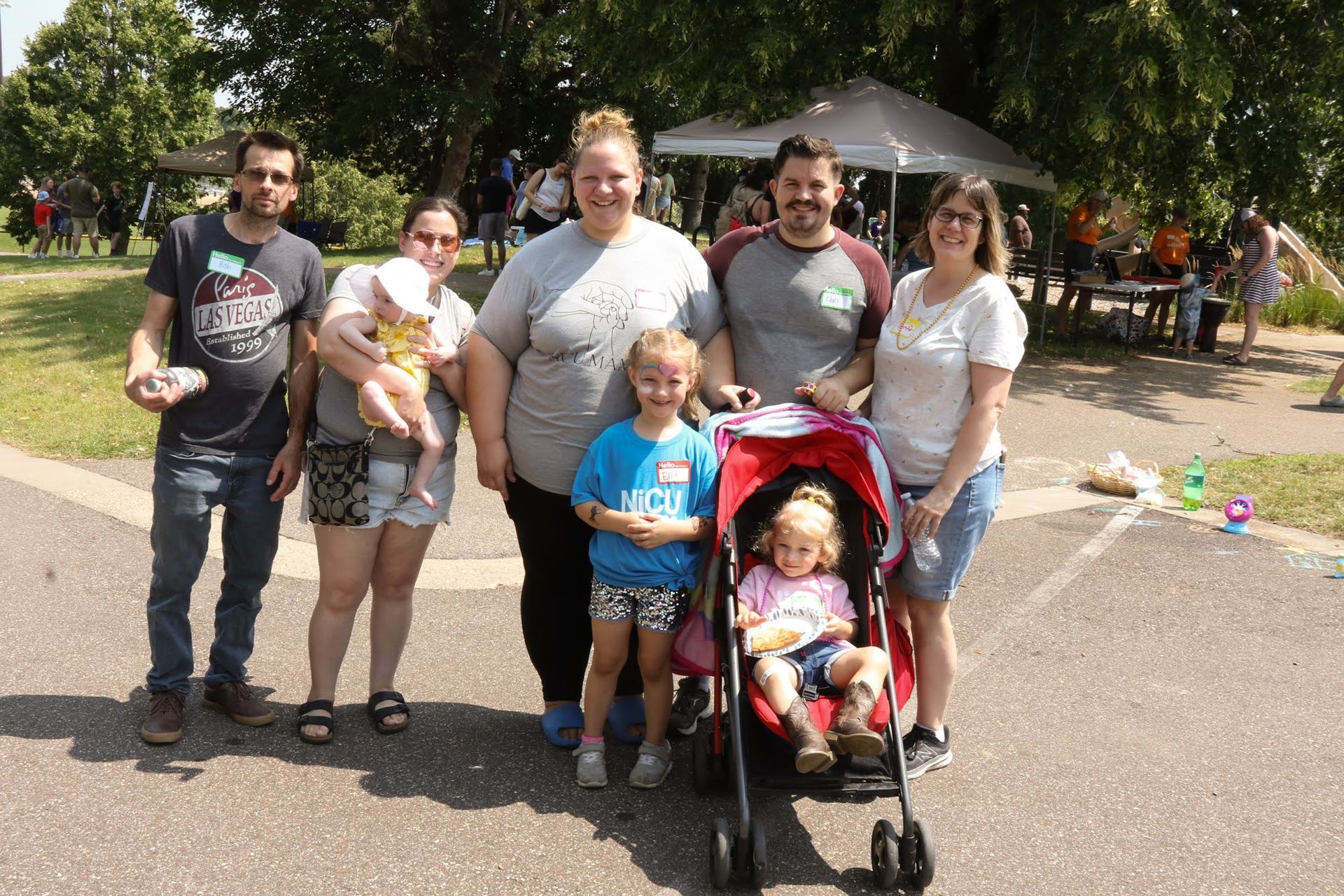 Group of six people posing outdoors with two young children and a stroller.