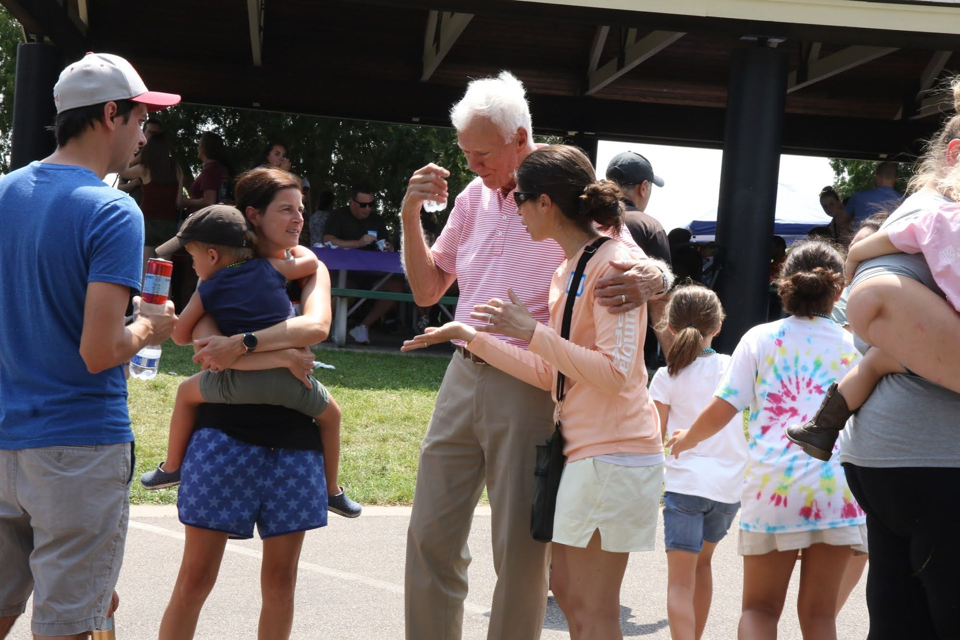 People outdoors; man dances with arms raised; others watch.