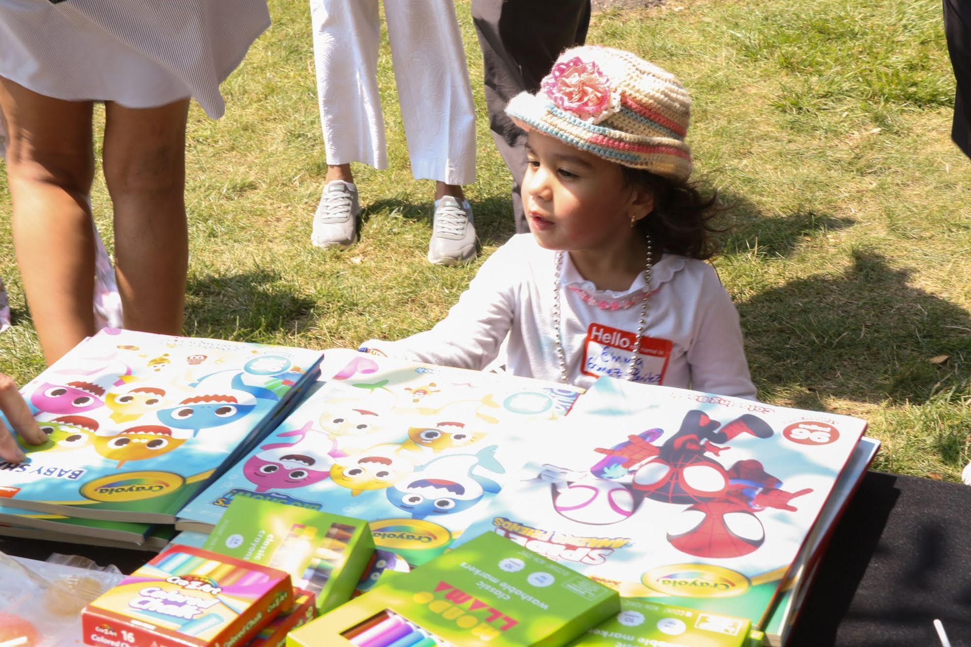 Girl at table looking at books; outdoor setting.