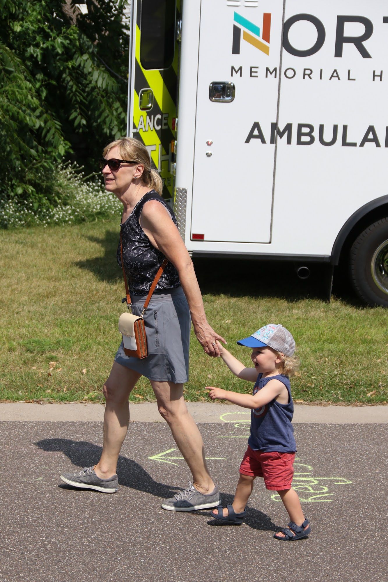 Woman and small child walking, holding hands, near an ambulance.