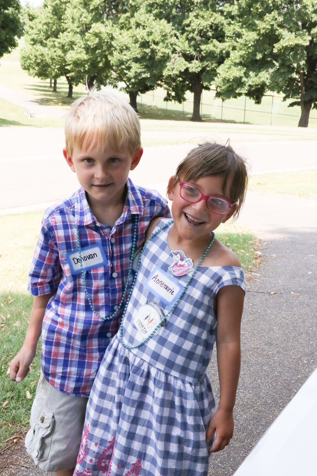 Boy and girl with name tags, smiling and posing outdoors.