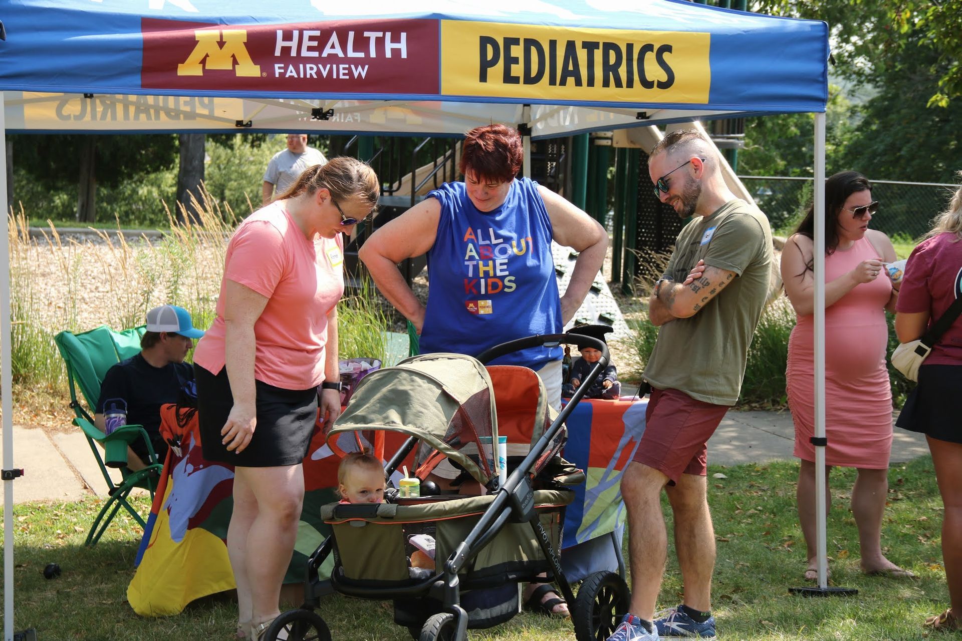 People looking at a baby in a stroller at a Health Fairview Pediatrics booth.