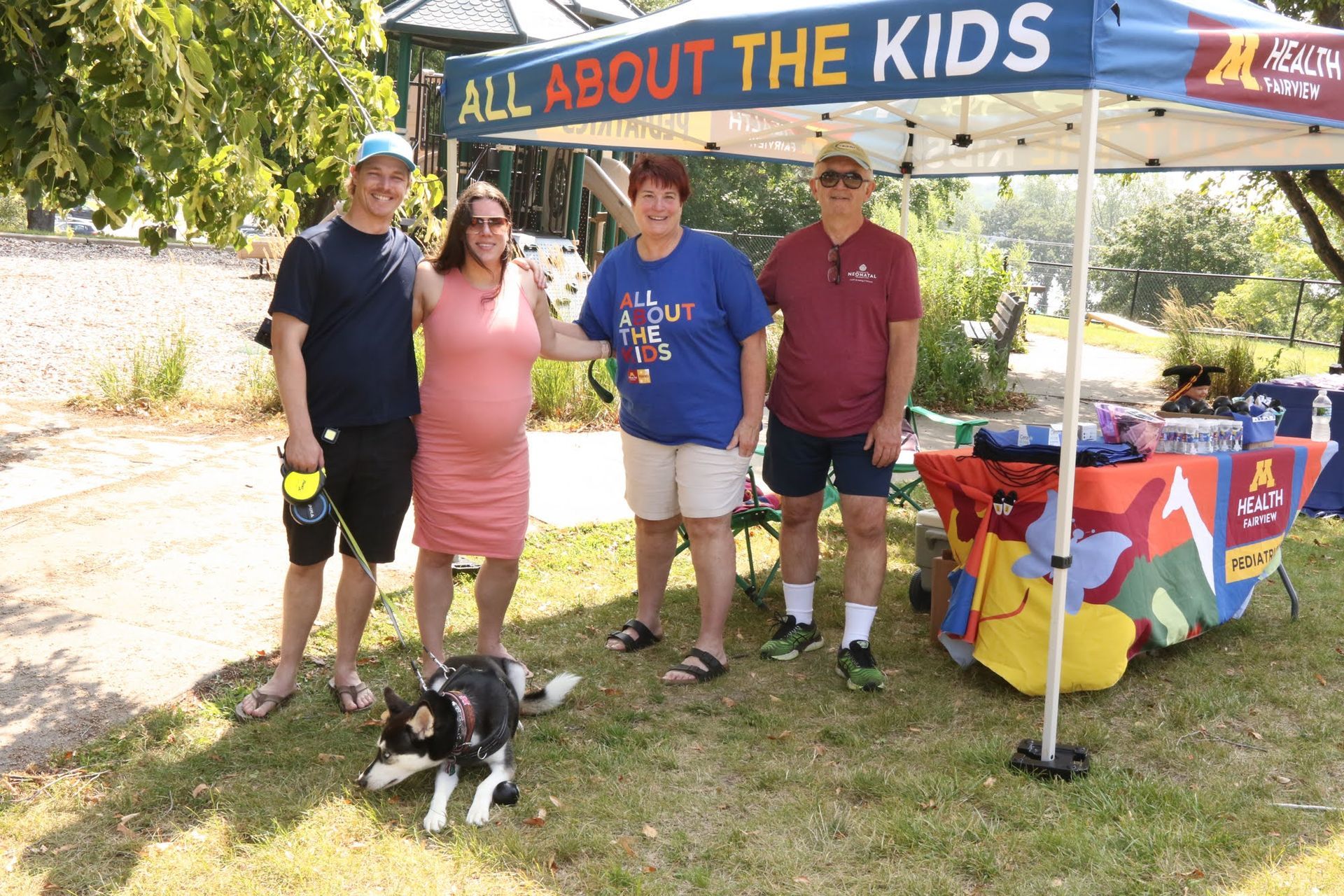 Four people stand near a tent that reads 