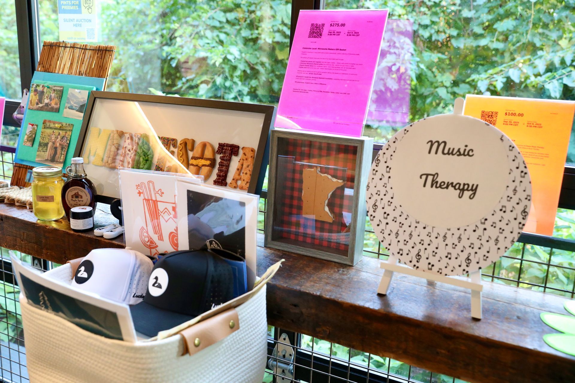 Display of items for music therapy: hats, signs, framed artwork, snacks, and a basket on a wooden ledge.