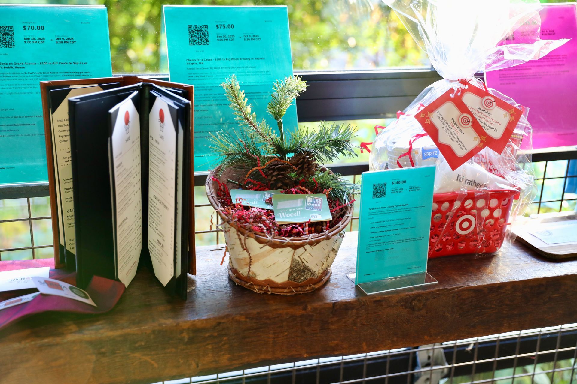 A display with open book, gift basket, and brochures on a wooden surface outdoors.