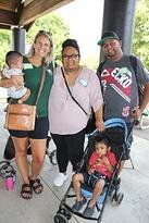 Two adults, two children, and a baby pose together outdoors at an event.