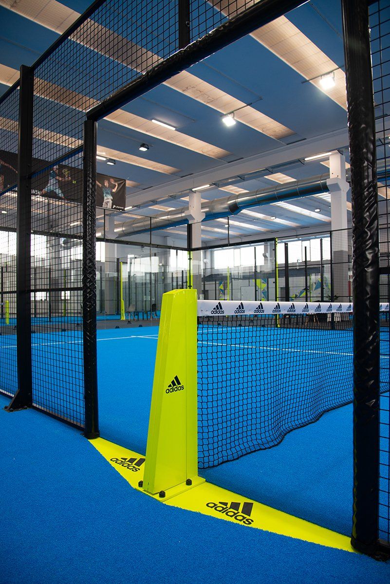 Campo da paddle tennis con pennarello giallo brillante con il logo Adidas, pavimento e rete blu.
