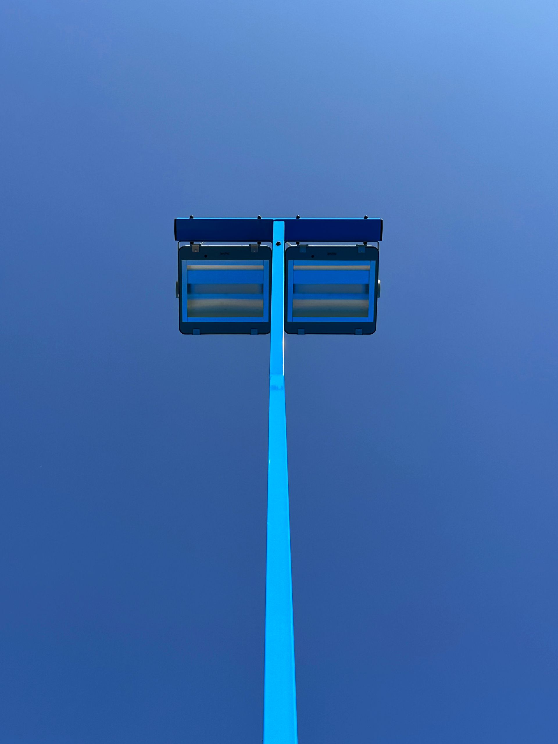 Lampione blu contro un cielo azzurro terso, con due lampioni rettangolari.
