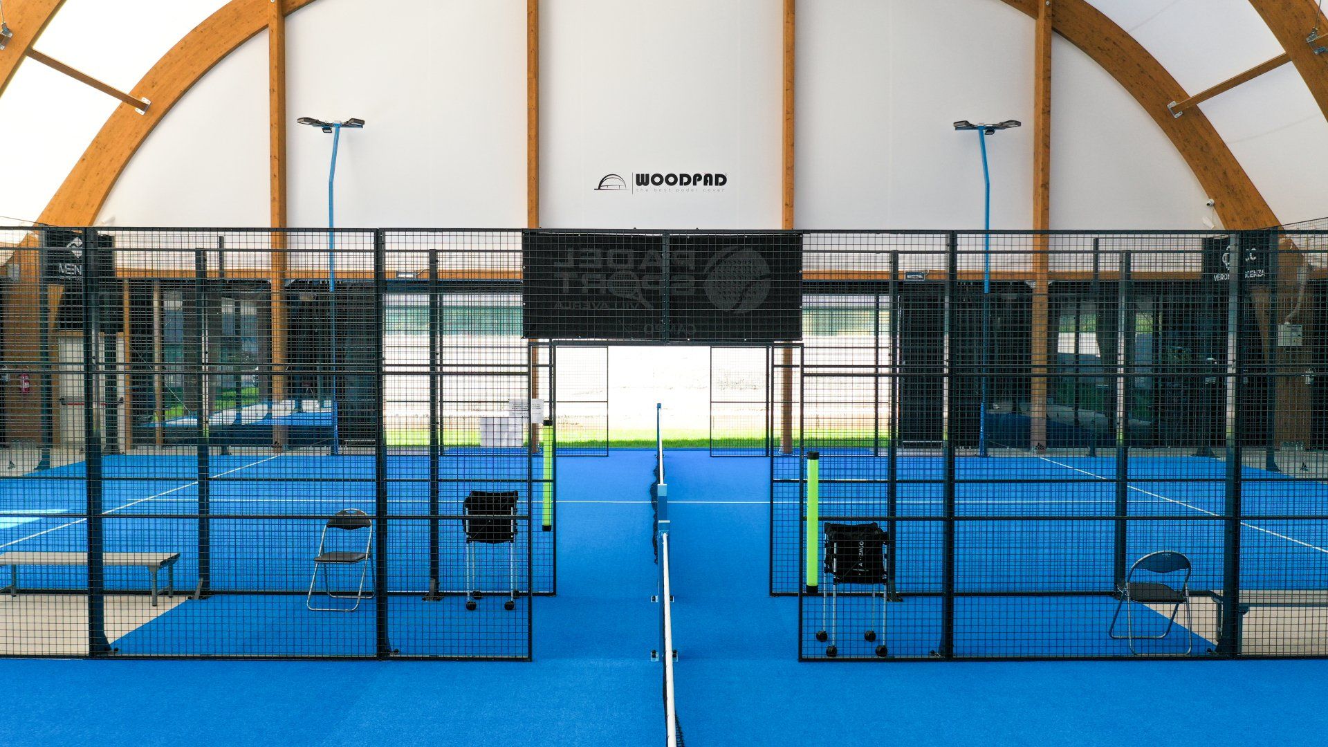 Campo da padel al coperto, superficie blu, recinzione in metallo nero, 