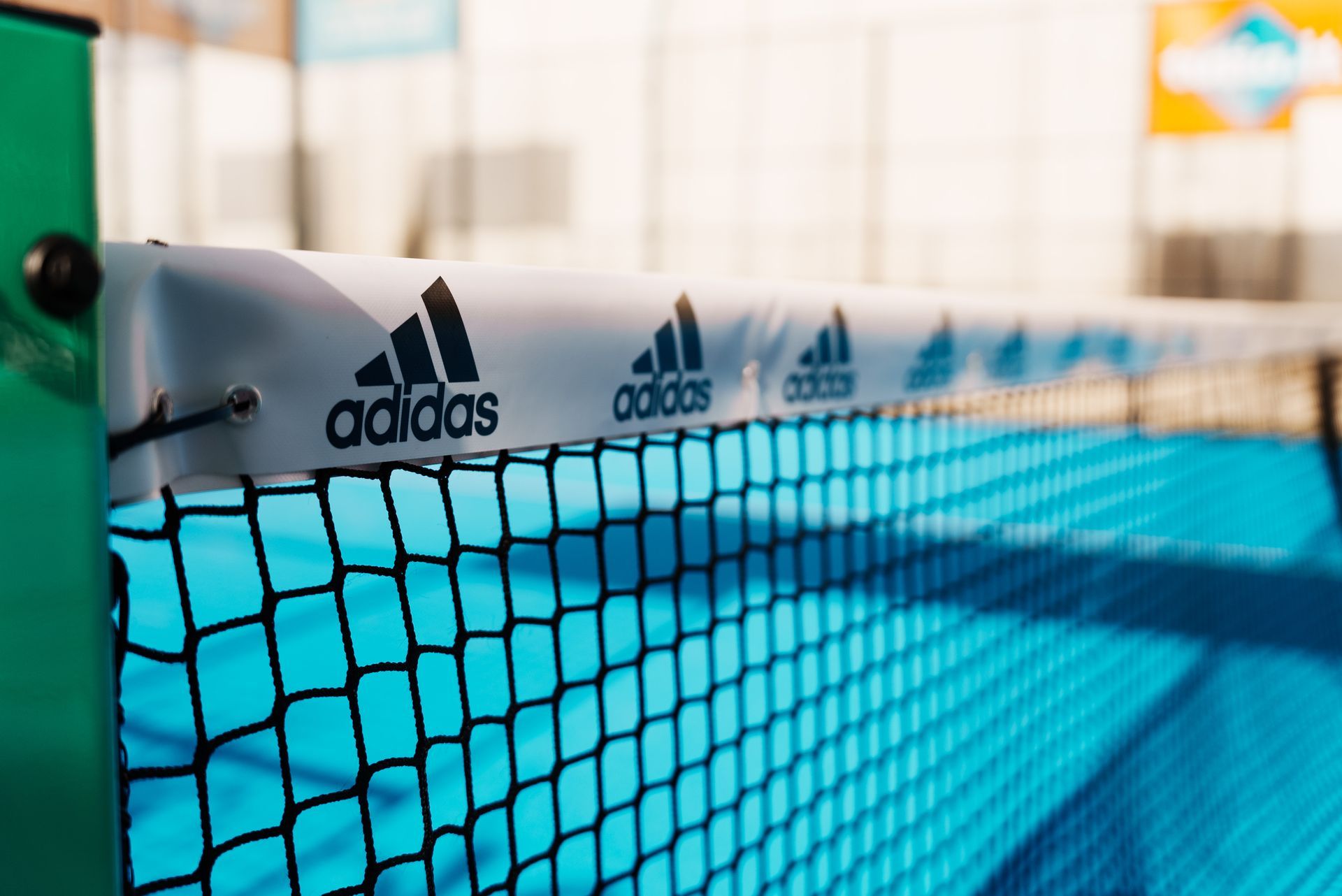 Primo piano di una rete sportiva con il marchio Adidas su un campo blu.