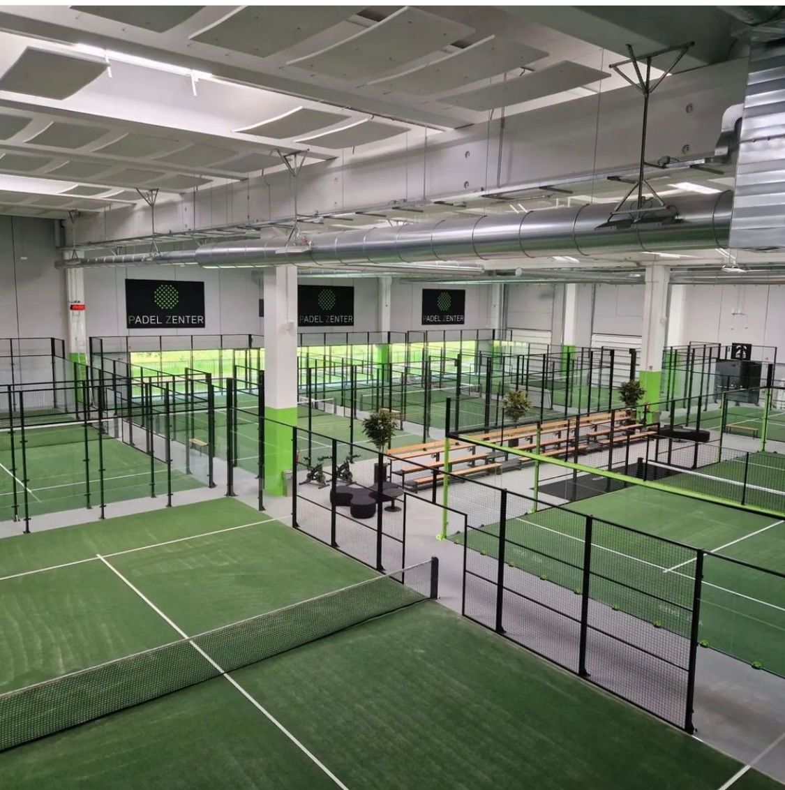 Impianto coperto per il padel tennis con più campi e manto erboso verde.