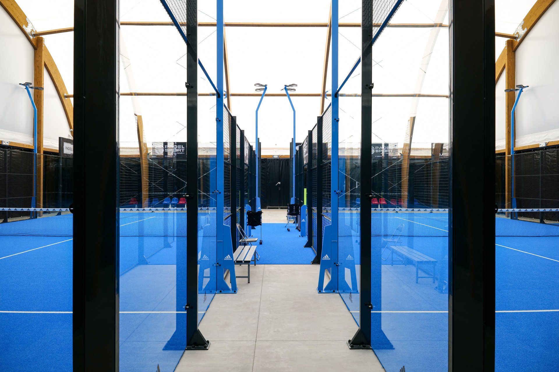 Campo da padel blu al coperto con pilastri neri e rete blu.