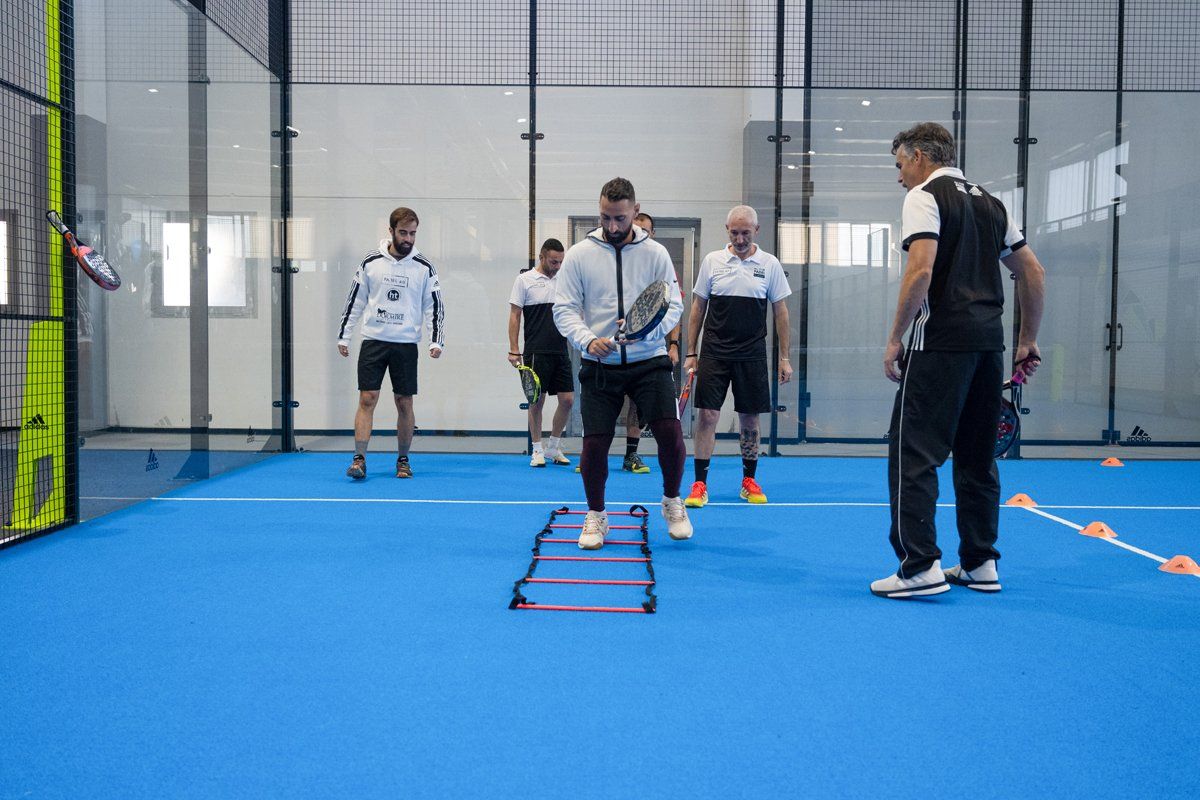 Allenamento di padel: uomo con racchetta che si esercita sulla scala di agilità; l'allenatore osserva.