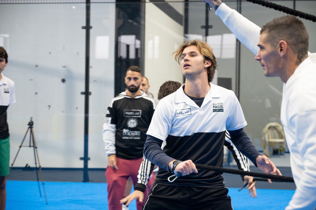 Persone in palestra che usano le corde per fare esercizio, sotto la guida di un allenatore.
