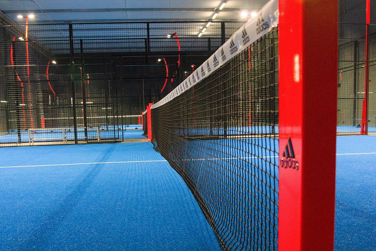 Palo rosso con il marchio Adidas in un campo da padel con pavimentazione blu.