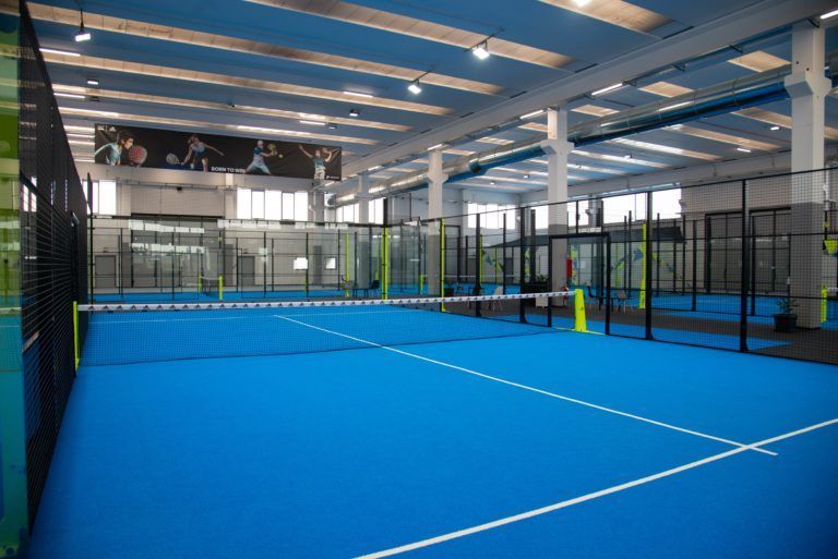 Campo da padel indoor con superficie blu e più campi.
