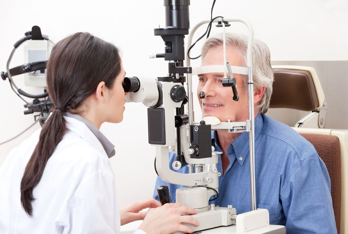 Optometrist examining a patient's eyes with a slit lamp in an eye clinic.