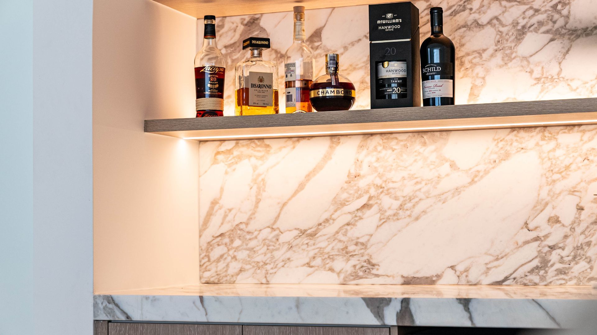 A Modern Kitchen With White Cabinets and Wooden Stools — Elite Stone in Gold Coast, QLD