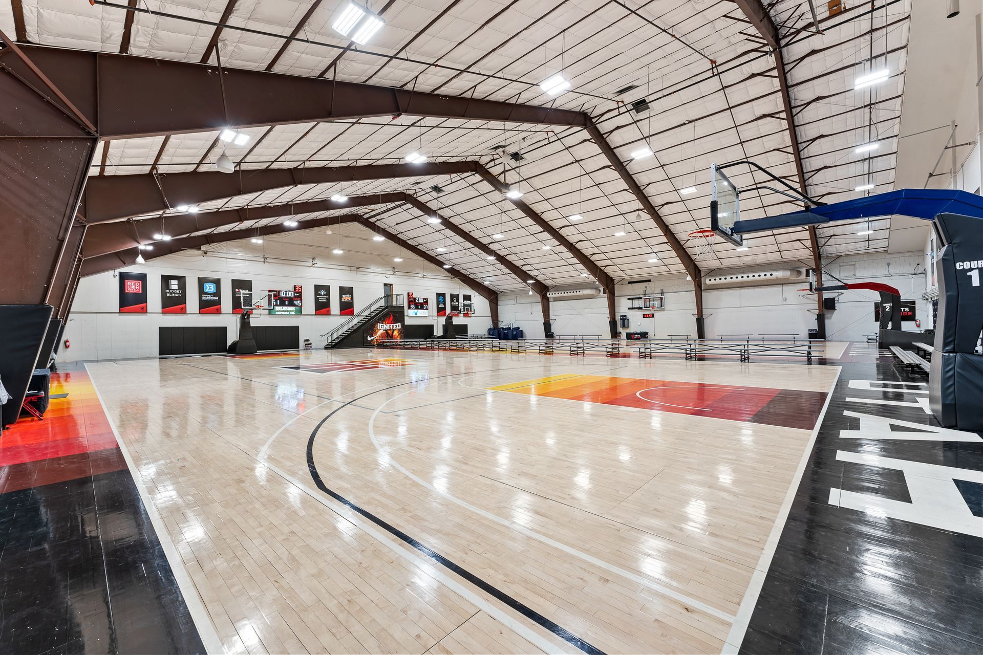 A large indoor basketball court with a wooden floor and a basketball hoop.