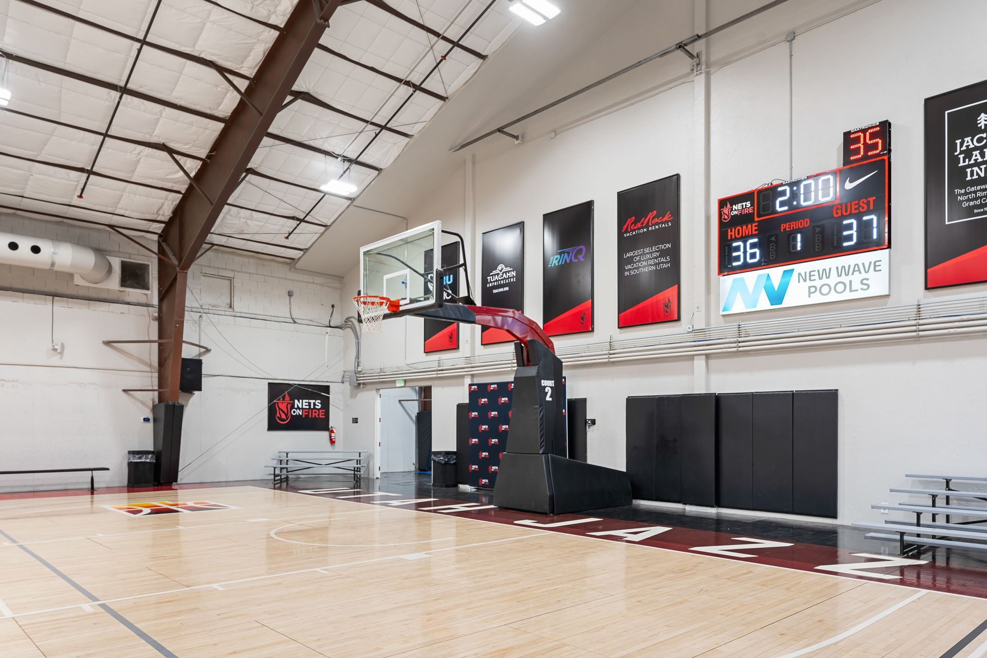 A basketball court in a gym with a scoreboard on the wall.