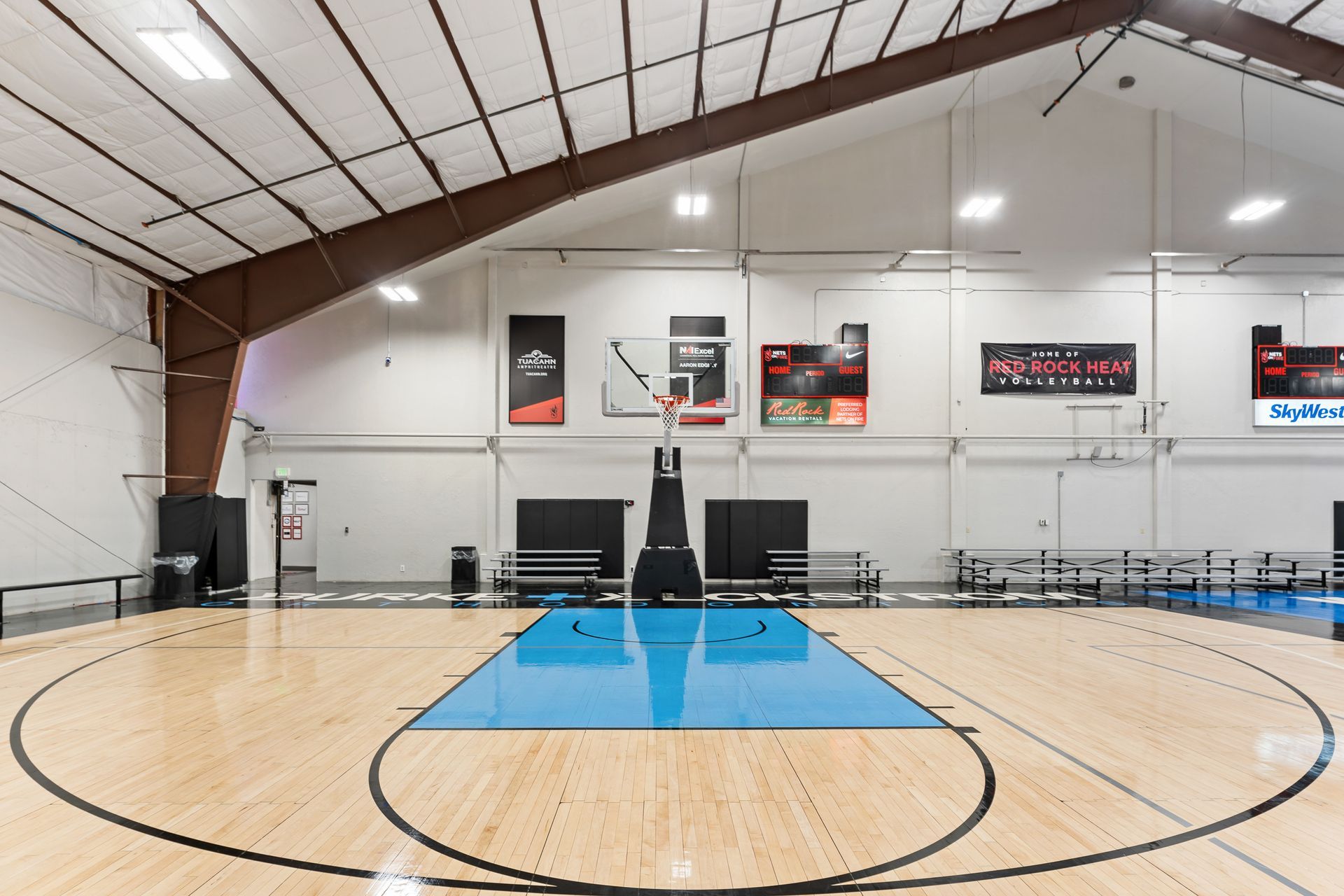 A large indoor basketball court with a blue court and a basketball hoop.