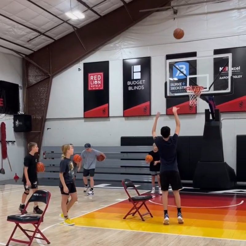 A group of kids are playing basketball in a gym with a sign that says red lion