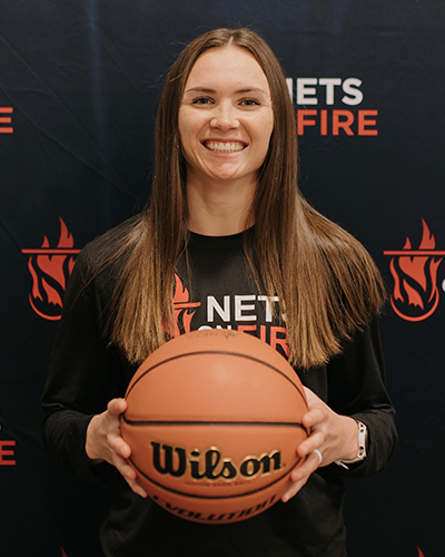 A woman in a black shirt is holding a wilson basketball.