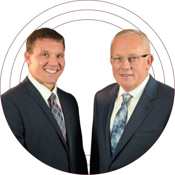 Two men in dark suits and patterned ties posing against a white background with circular rings