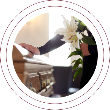 Person placing white flowers on a casket during a funeral service