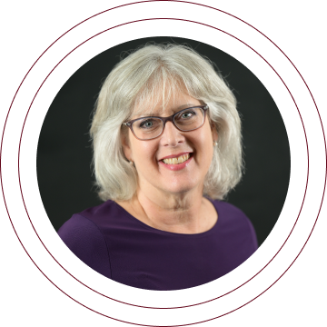 Portrait of a smiling woman with glasses in a purple top, framed by circular rings on a dark background