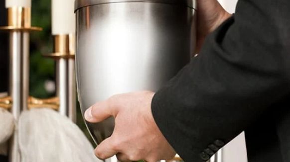 Hand placing a stainless steel cocktail shaker on a bar counter