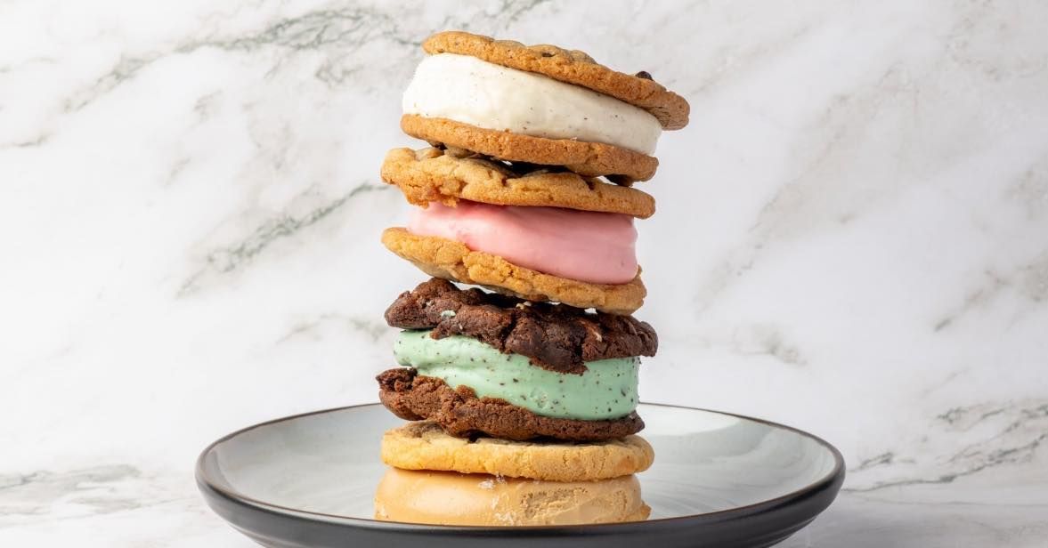 Stack of colorful cream-filled macarons on a gray plate against a marble background