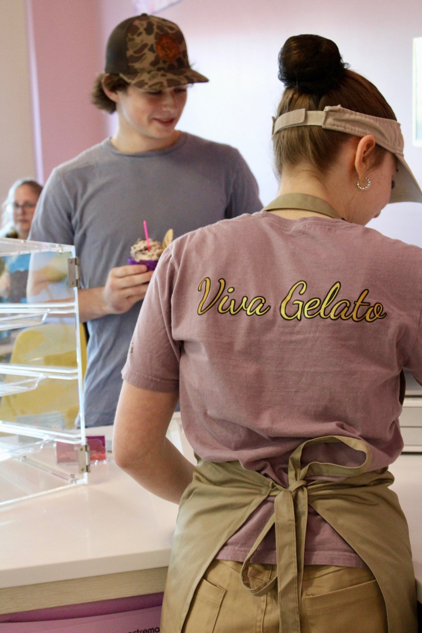 Two people in aprons preparing food at a counter at viva gelato