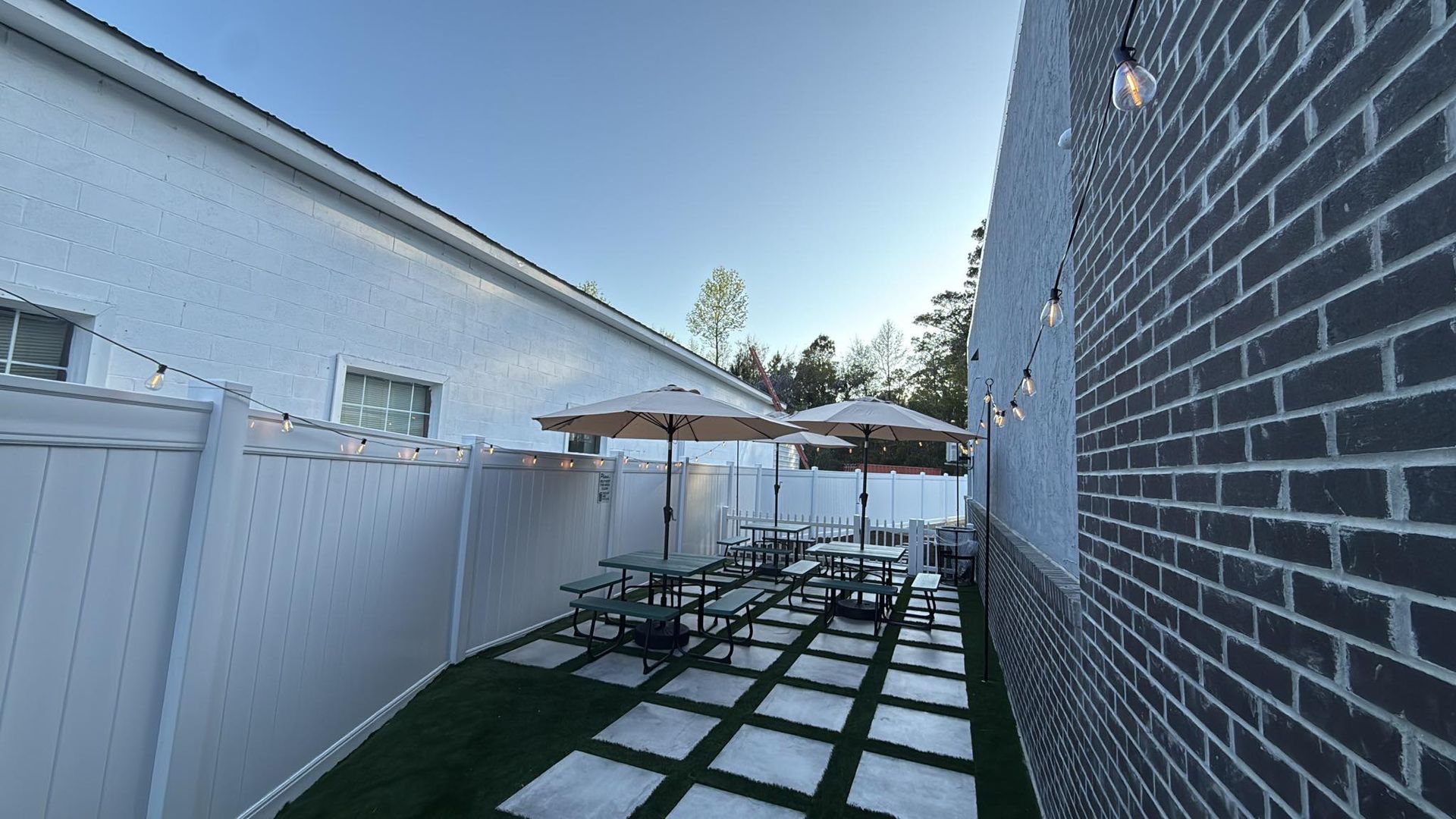 Outside seating at Viva Gelato patio with picnic tables, white fencing, and brick wall beside a house