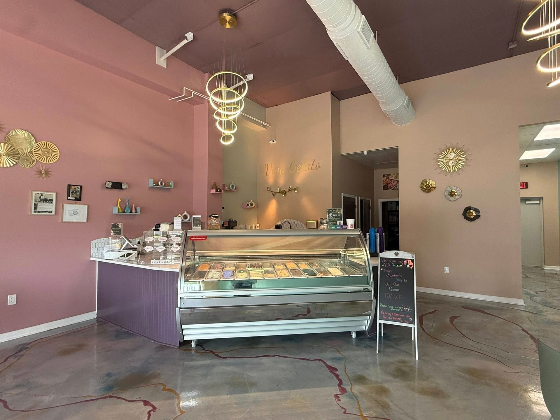Bakery display case in a pink shop with hanging lights and wall decor