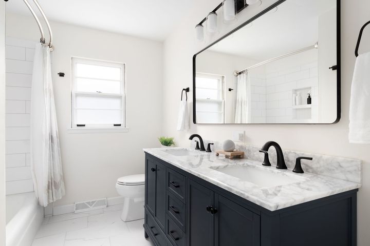 A bathroom with two sinks , a toilet , and a large mirror.