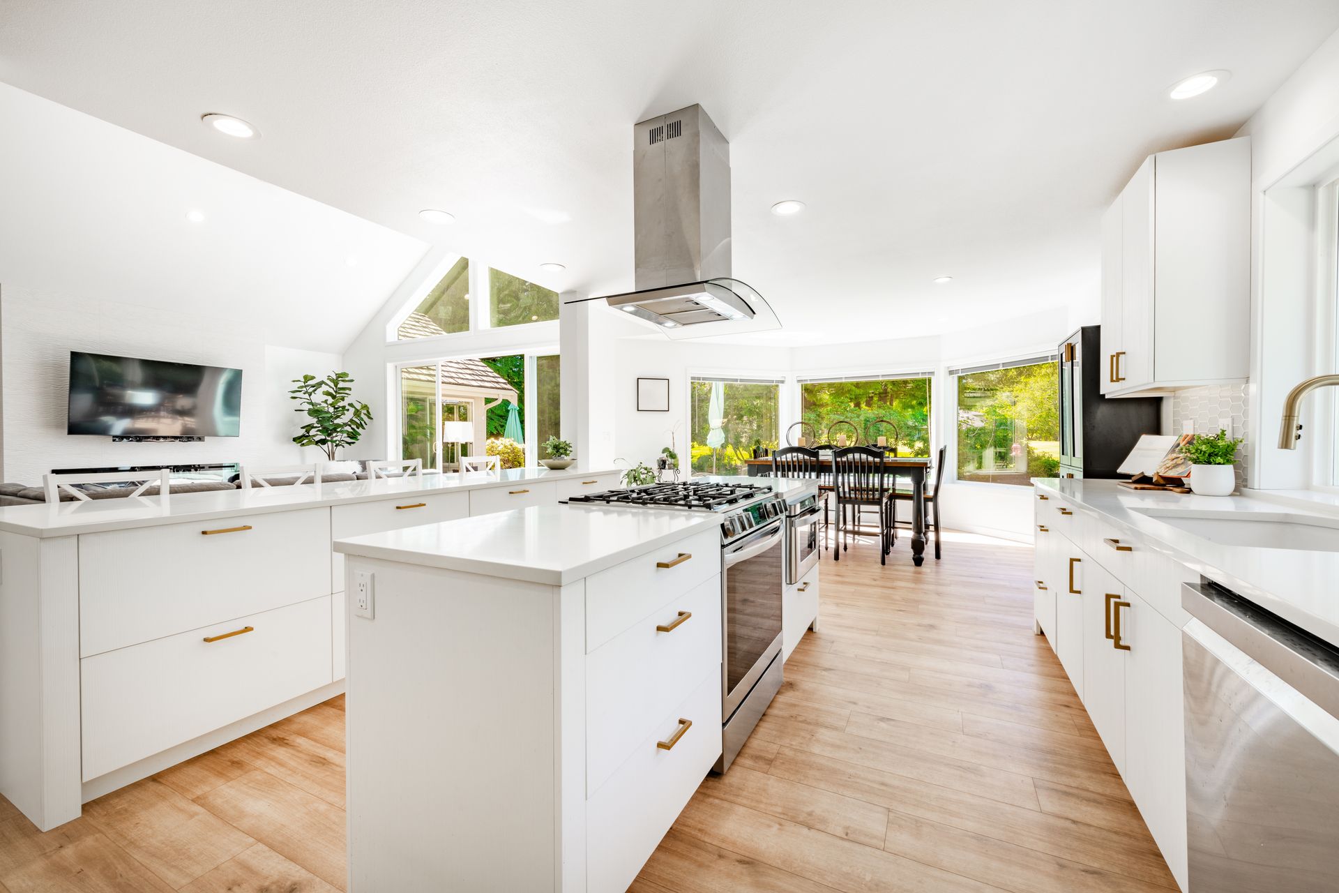 A kitchen with white cabinets and stainless steel appliances and a large island in the middle.