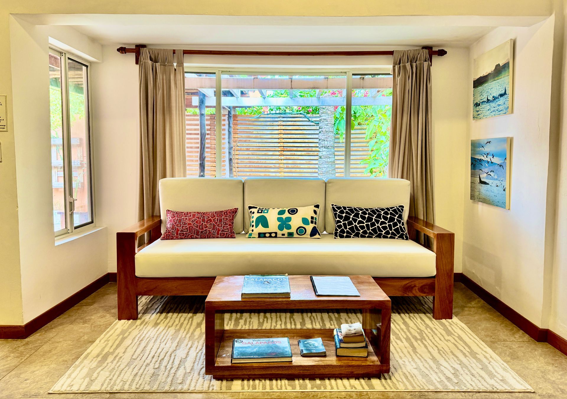 Cozy living room with a beige sofa, patterned pillows, coffee table, and large window blinds