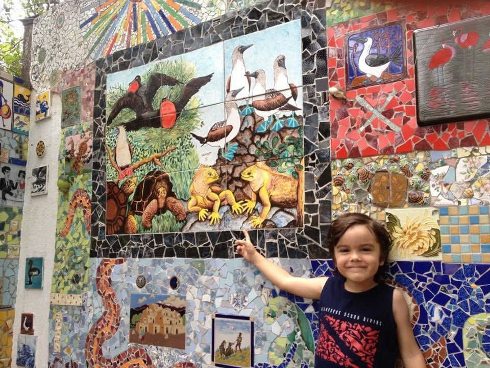 Child pointing at colorful mosaic mural with animals and birds