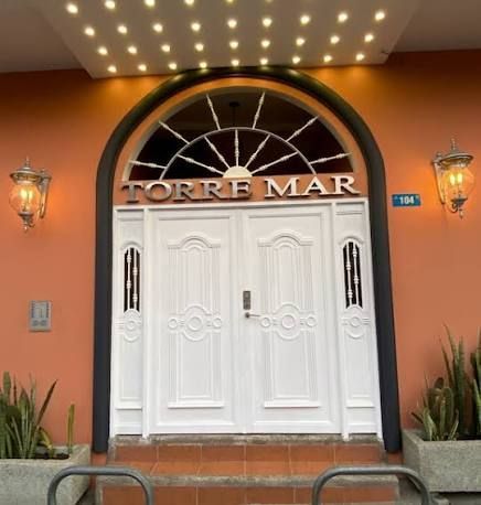 Front entrance to TORRE MAR with white double doors, arched window, and warm orange walls under lights