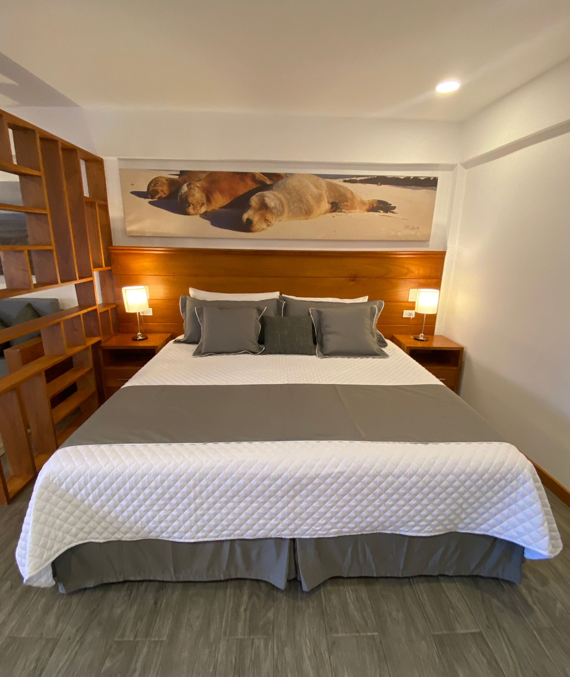 Cozy bedroom with a made bed, wooden headboard, wall art, and bedside lamps