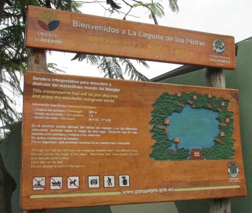 Wooden welcome sign for Laguna de las Minas, with Spanish text and a map illustration in Galapagos.