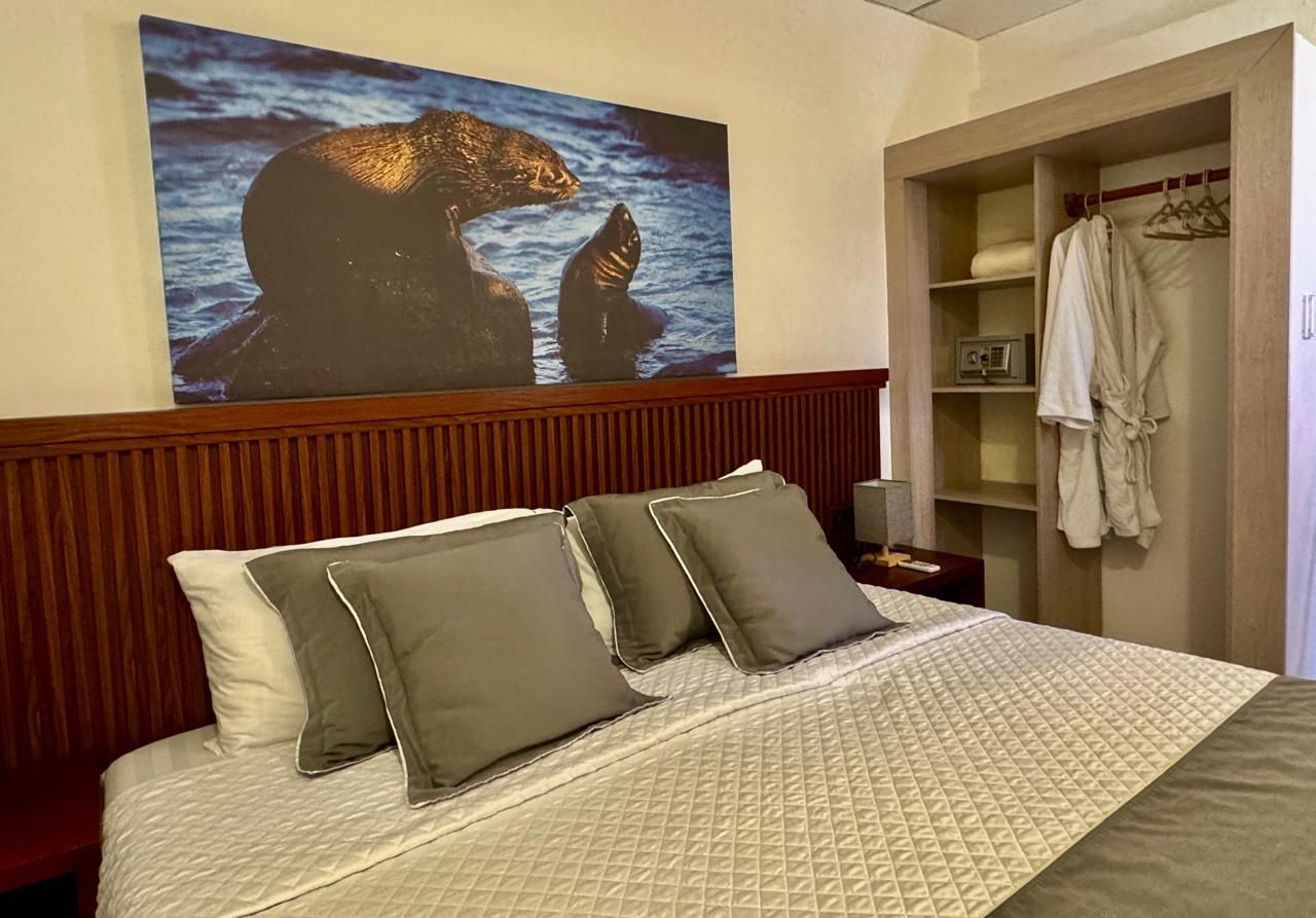 Cozy bedroom with a neatly made bed, pillows, wooden headboard, and open closet with hanging clothes