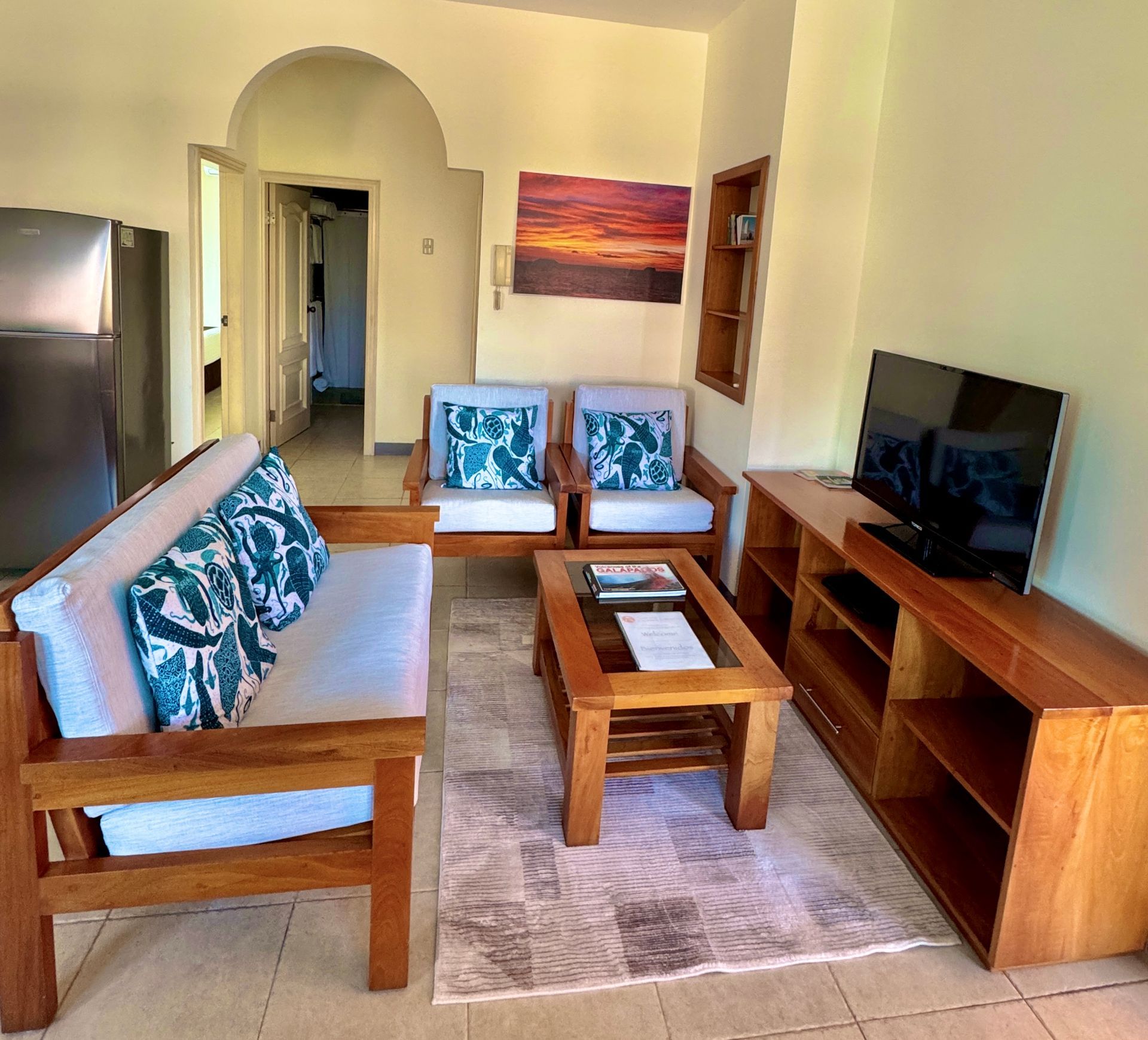 Galapagos hotel Living room with wooden furniture: a sofa, loveseat, coffee table, and TV stand.