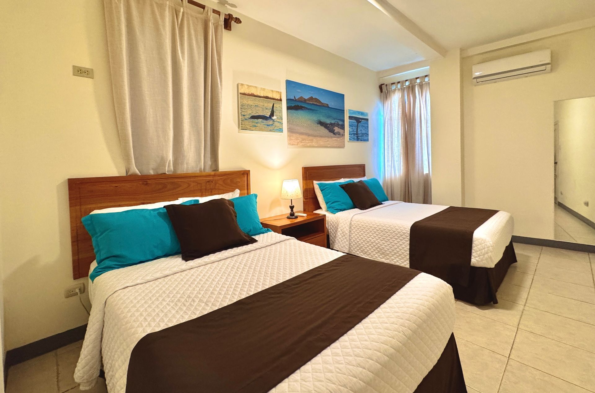 Galapagos hotel Two double beds in a brightly lit room with brown and teal bedding.