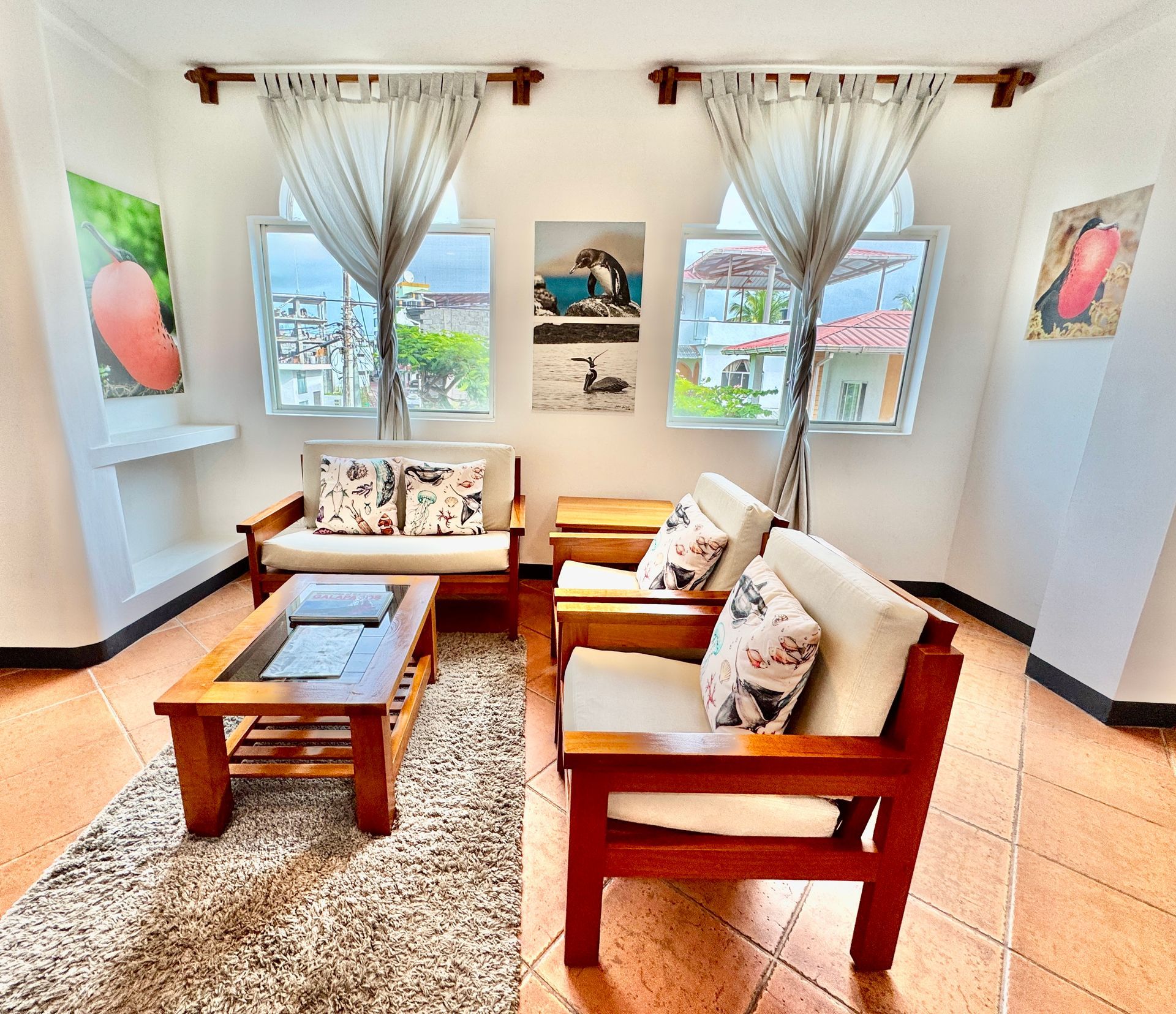 Galapagos hotel Cozy living room with wooden furniture, beige cushions, and artwork.