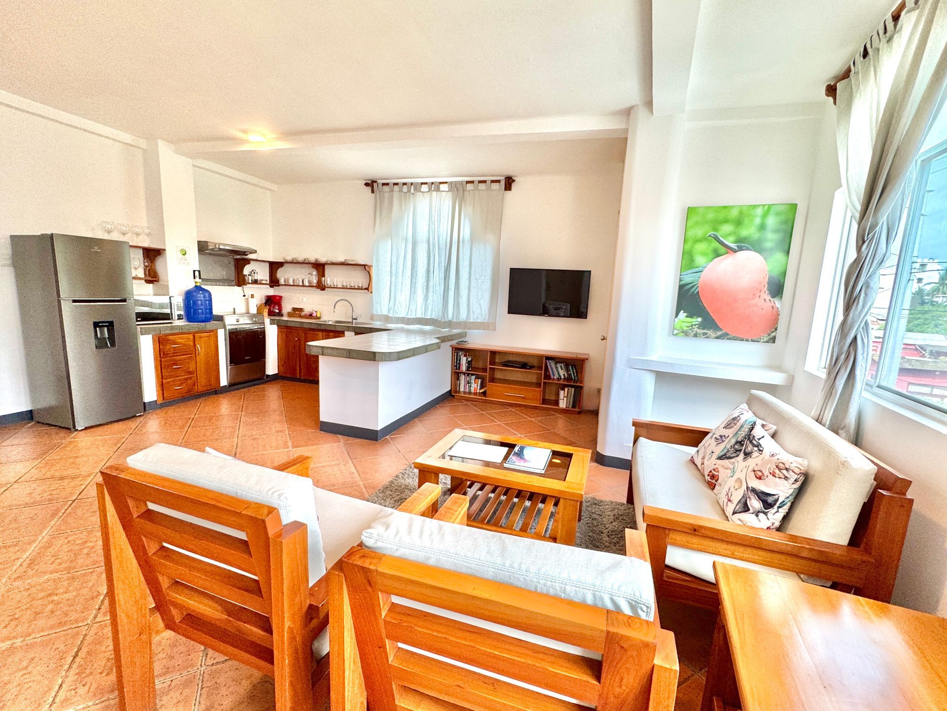 Galapagos hotel Living area and kitchen with wooden furniture and a stainless steel refrigerator.