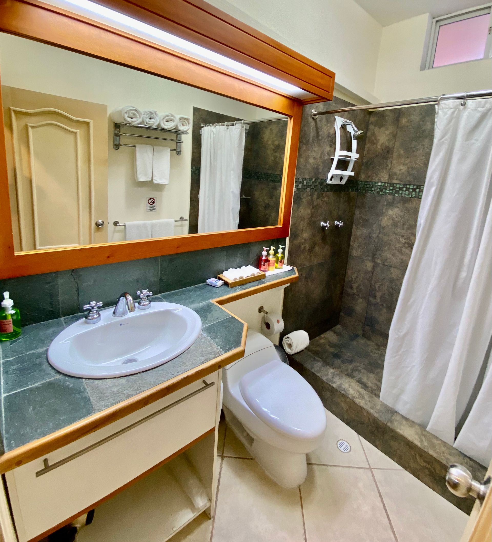 Galapagos hotel Bathroom with a sink, toilet, and shower. The shower has a white curtain, and the sink area.